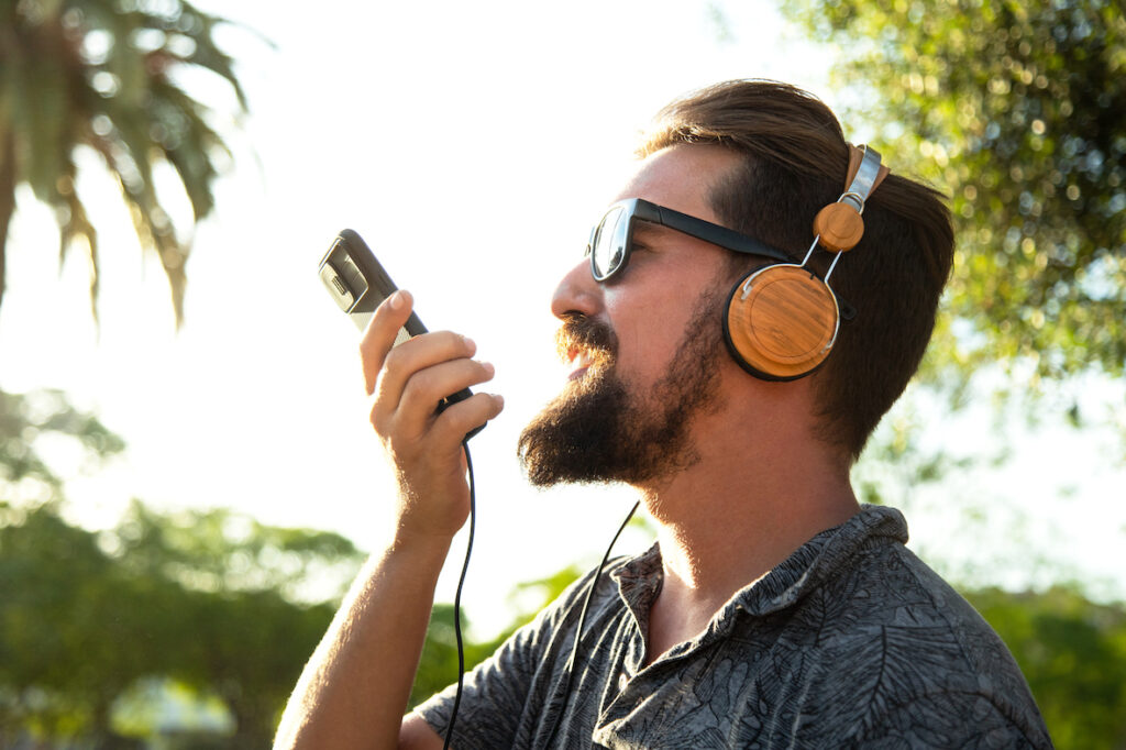 Un homme portant un casque utilise une application de synthèse vocale pour convertir ses mots en texte et les envoyer à un ami.